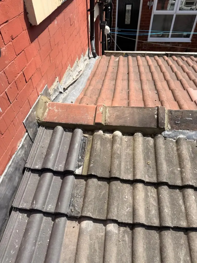 Wider view of a rear extension roof with restored ridge tiles and weathered concrete pantiles.