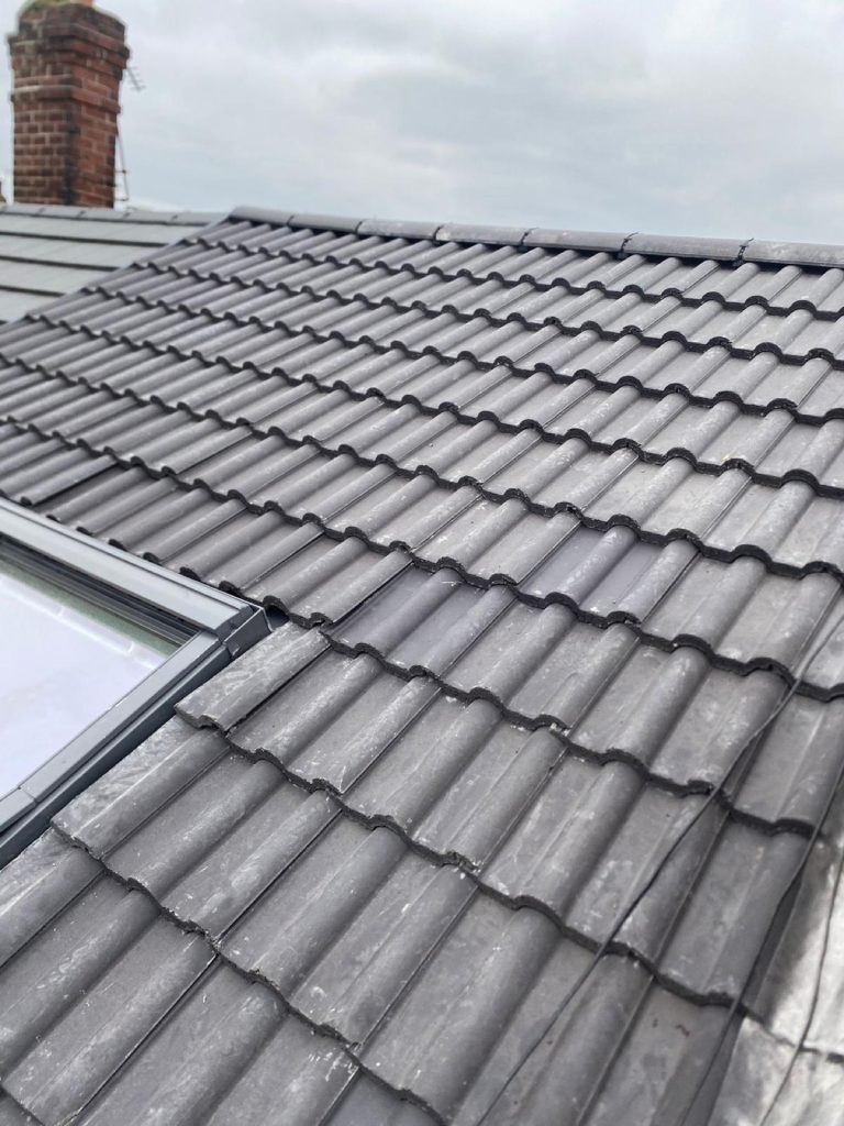 New charcoal roof tiles with two Velux skylights freshly fitted on a Leeds terrace, terraced houses behind.