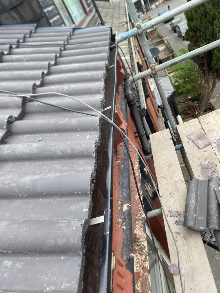 Up-close detail showing freshly pointed roof tile end with a brick chimney pot in the foreground.