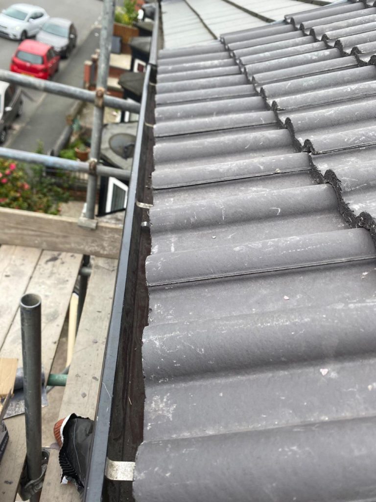 Down-the-roof view of new tiles with scaffolding and a Leeds residential street below.