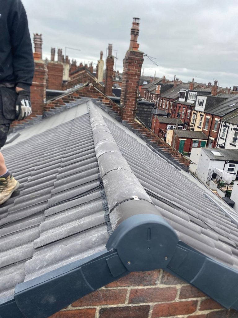 Close-up of new roof tiles meeting a red brick chimney with a freshly cast lead apron flashing.