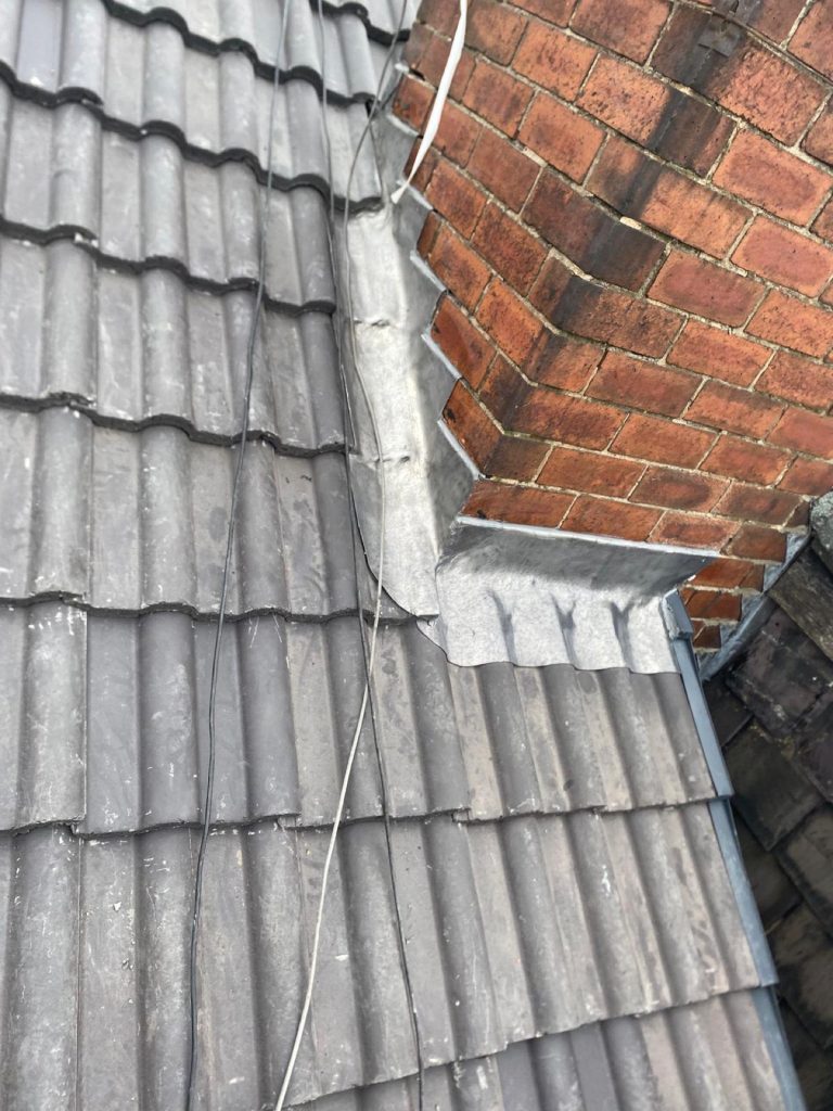 Single Velux skylight installed in new charcoal concrete roof tiles with a smaller Velux higher up the slope.