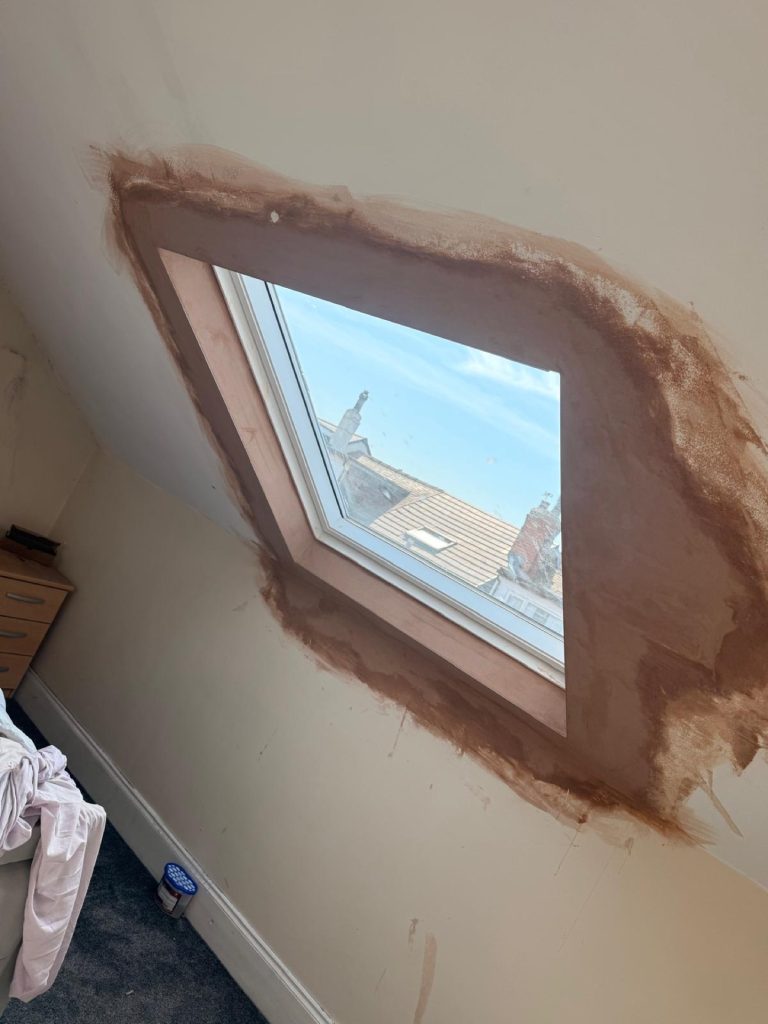 Newly installed Velux skylight in a Leeds loft conversion, freshly plastered surround, sky and Leeds rooftops visible through the glass.